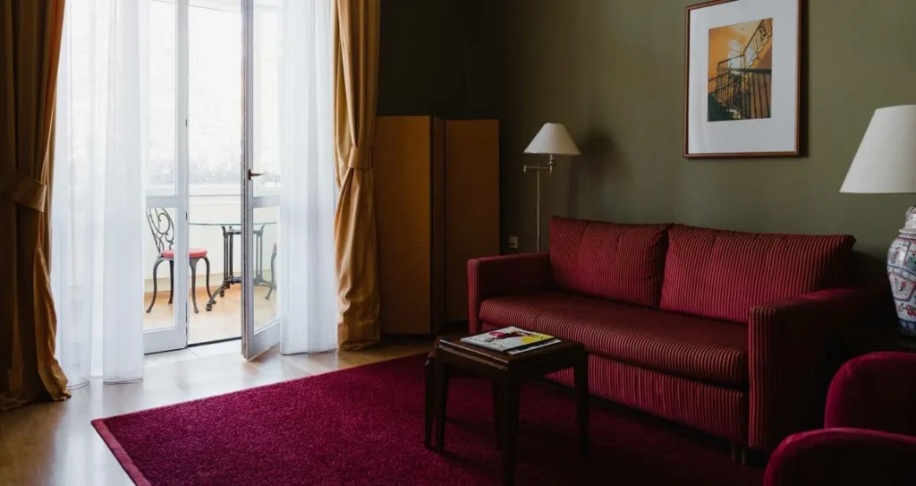 Warmes Ambiente des Wohnbereichs im Deluxe Zimmer mit Blick auf den Balkon und Sitzgarnitur