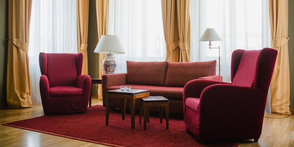 Familienzimmer im Hotel Louisa's Place in Berlin mit rotem Sofa und roten Sesseln.
