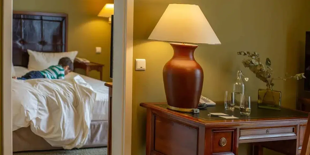 Nobler Schreibtisch mit Tischleuchte und Blick auf das Bett im Familienzimmer des Louisa's Place Hotel Kudamm Berlin