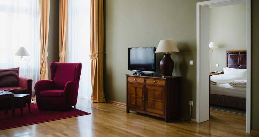 Hölzernes Sideboard mit Lampe und Flatscreen und Blick in das Schlafzimmer der Louisa's Suite im Boutiquehotel am Kudamm