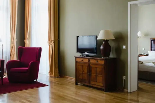Hölzernes Sideboard mit Lampe und Flatscreen und Blick in das Schlafzimmer der Louisa's Suite im Boutiquehotel am Kudamm