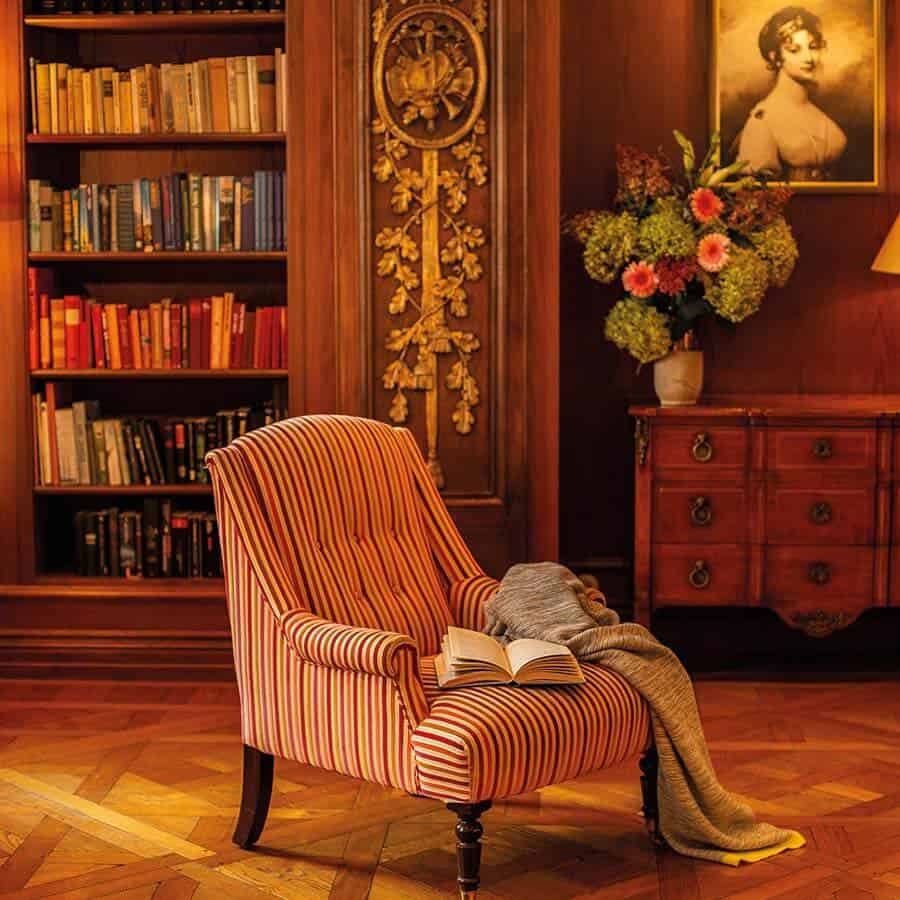 Gestreifter Sessel und Bücherregal in fürstlich eingerichteter Bibliothek des Luisa's Place Hotel Berlin