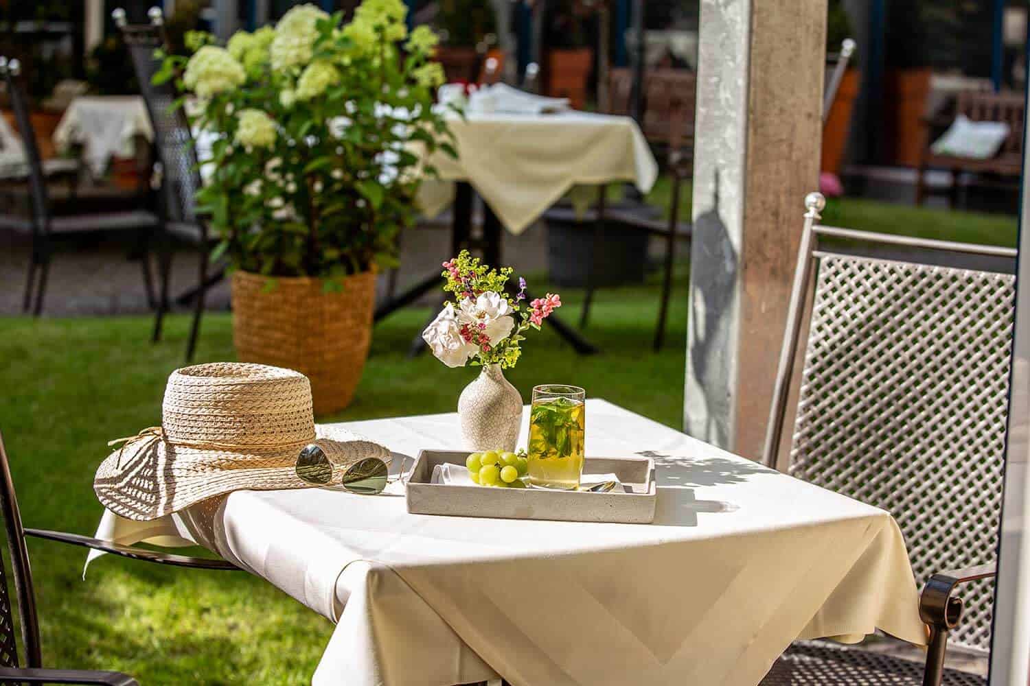 Sommerlich gedeckter Tisch mit Blumen und Getränk im Garten von Louisa's Place Hotel am Kudamm Berlin