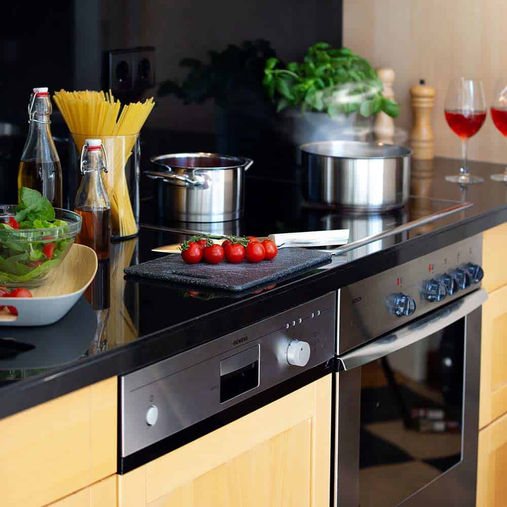 Ansicht der Küchenzeile im Premium Zimmer mit Spülmaschine und Herd, Kochtöpfen und frischen Esswaren