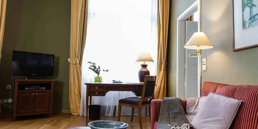 Gemütliches rotes Sofa mit Kissen und Decke und Flatscreen in der Louisa's Place Grand Suite