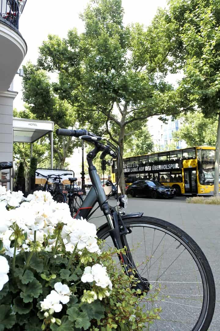 Fahrrad vor dem Louisa´s Place am Kurfürstendamm in Berlin. Im Hintergrund fährt ein gelber Doppeldeckerbus.