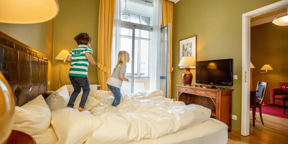 Zwei Kinder springen spielend rum auf dem Bett im Hotel Louisa´s Place am Kudamm in Berlin