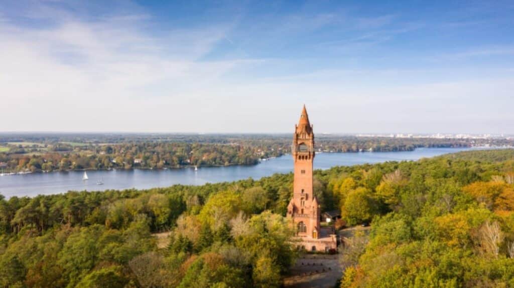 Der Grunewaldturm, wie er aus dem Grunewald hervorragt. Im hintergrund fließt die Havel.