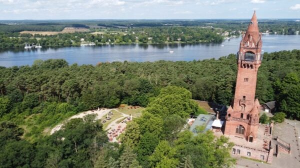 Der Grunewaldturm, wie er aus dem Grunewald hervorragt. Im hintergrund fließt die Havel.