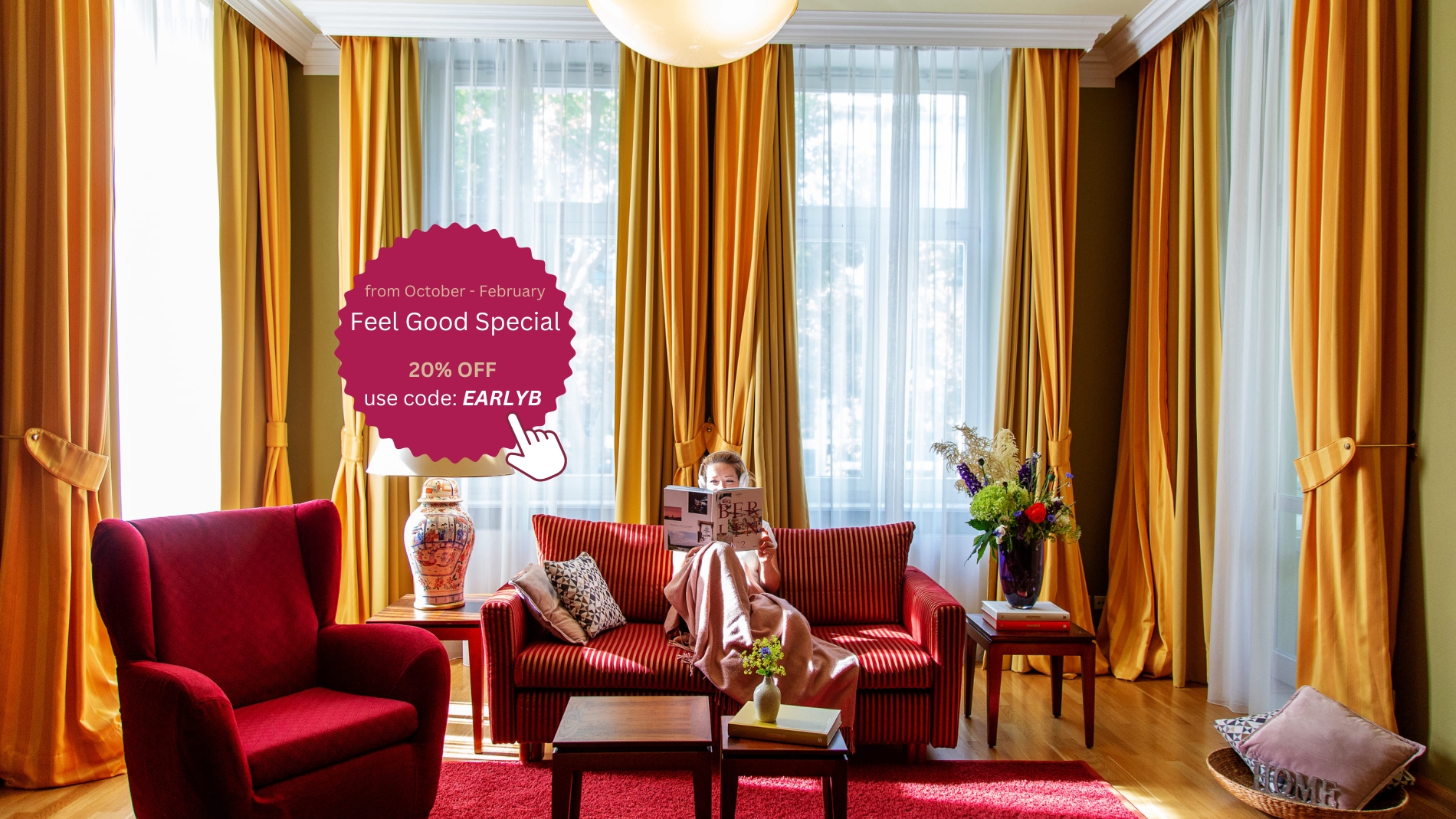 A woman sits on a sofa with a blanket and reads a magazine in the Grand Suite of Louisa's Place Hotel Berlin